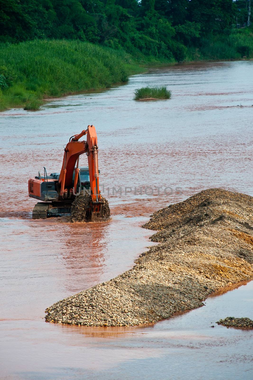 Excavator loader at river with raised bucket over blue sky by Yuri2012