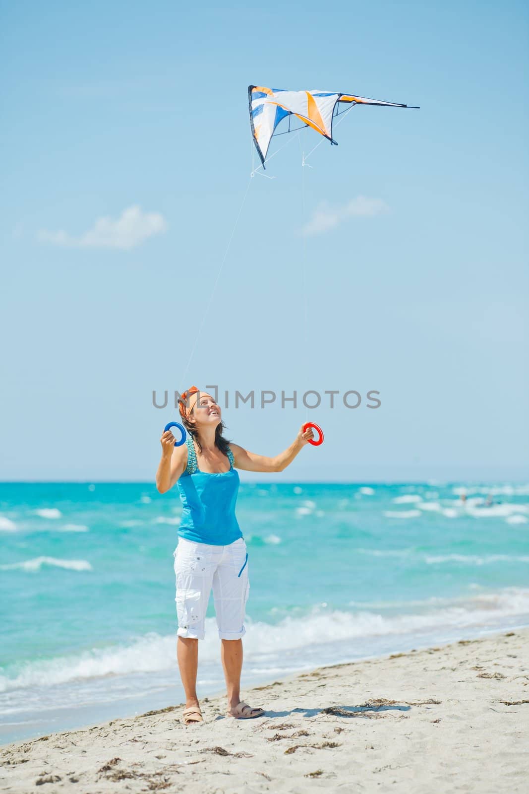 Young cute woman playing with a colorful kite on the tropical beach. Vertikal veiw