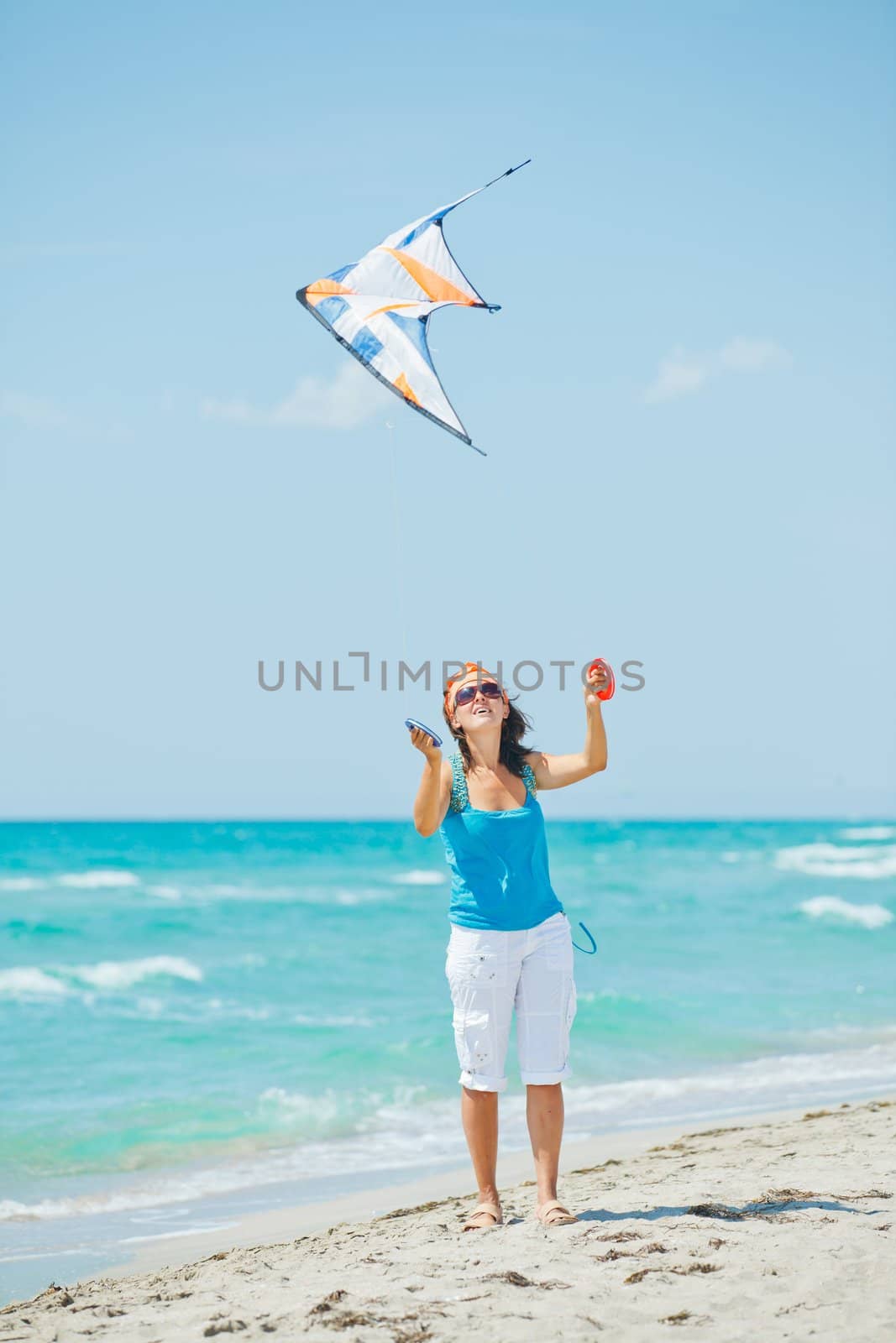 Young cute woman playing with a colorful kite on the tropical beach. Vertikal veiw