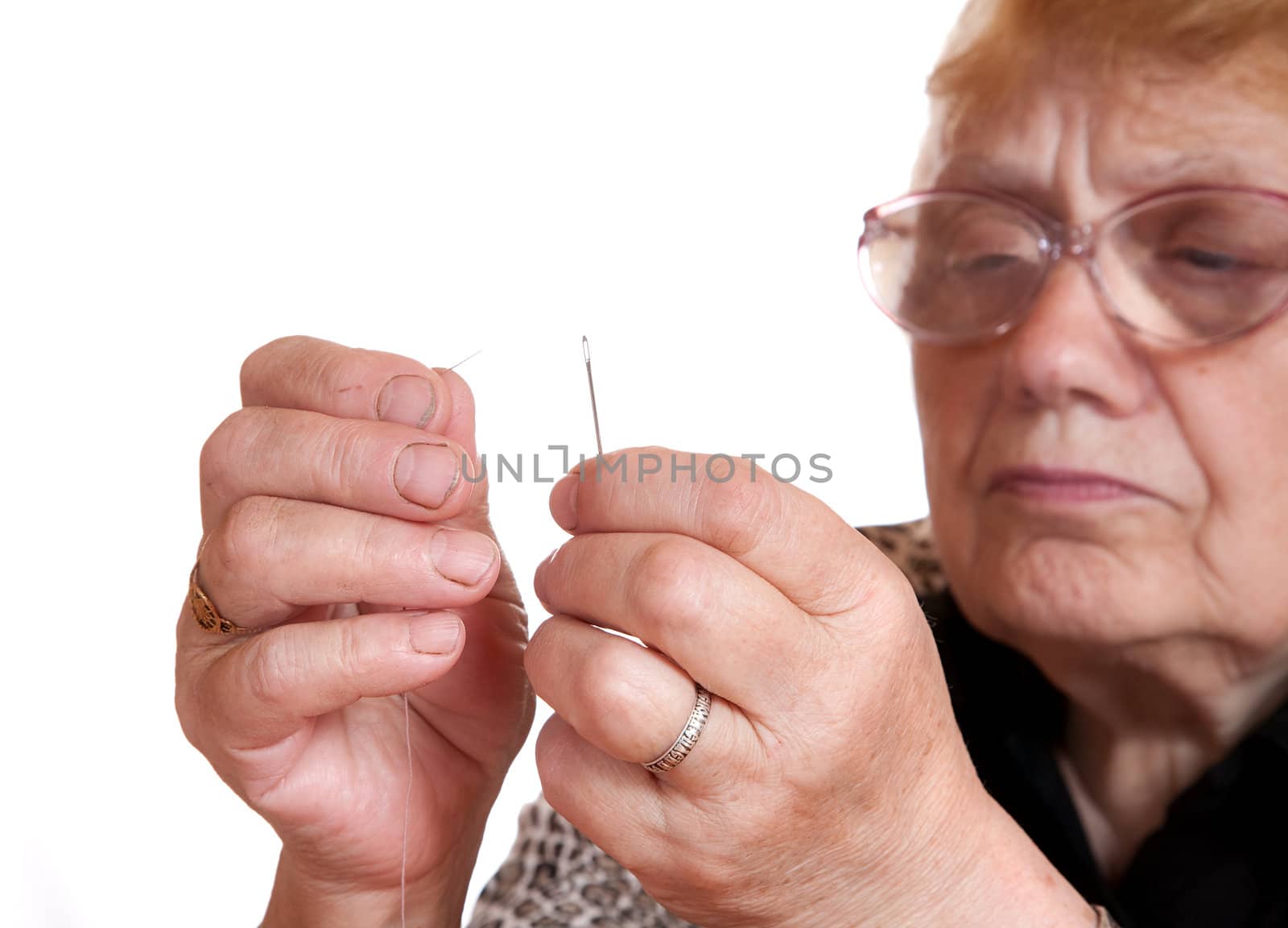 The old woman passes  thread in needle on  white background