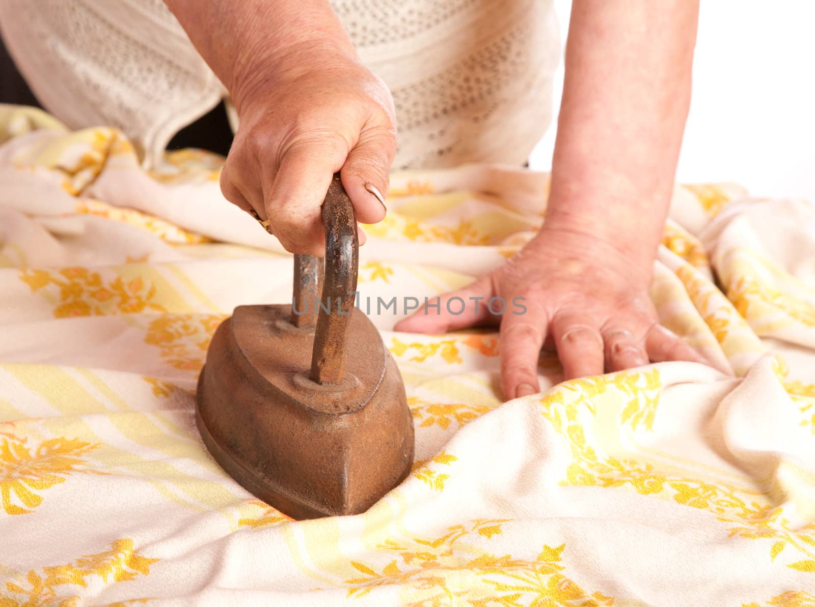 The old woman irons a cloth an ancient iron