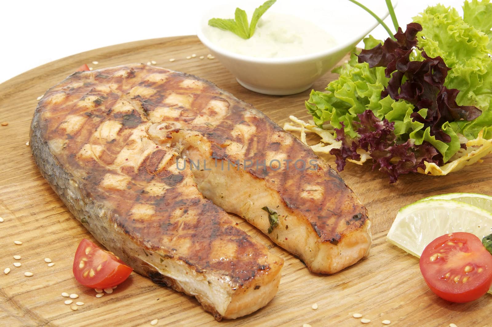 salmon steak cooking on the grill with fresh herbs and sauce