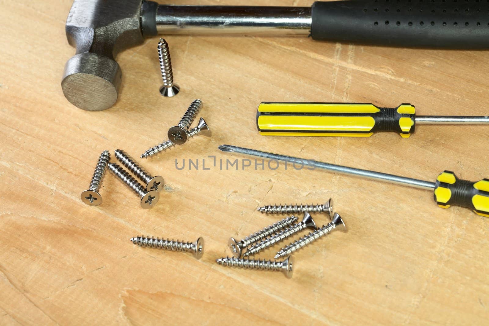 Hammer screw-driver screws on a wooden board