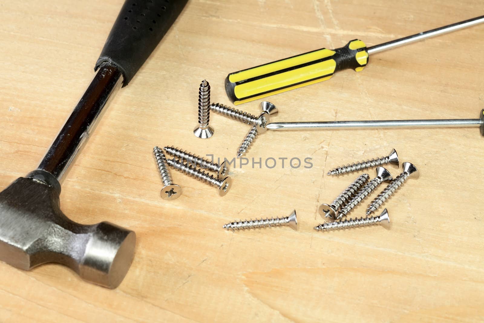 Hammer screw-driver screws on a wooden board