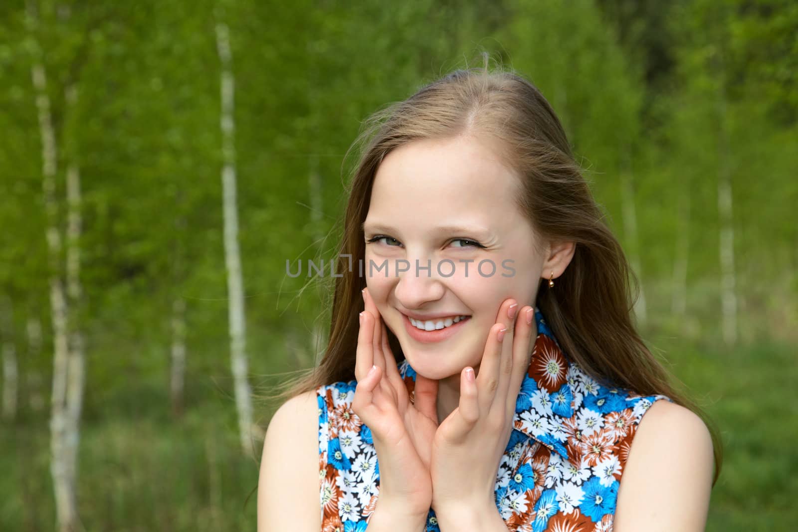 girl with a smile against young birches in the spring
