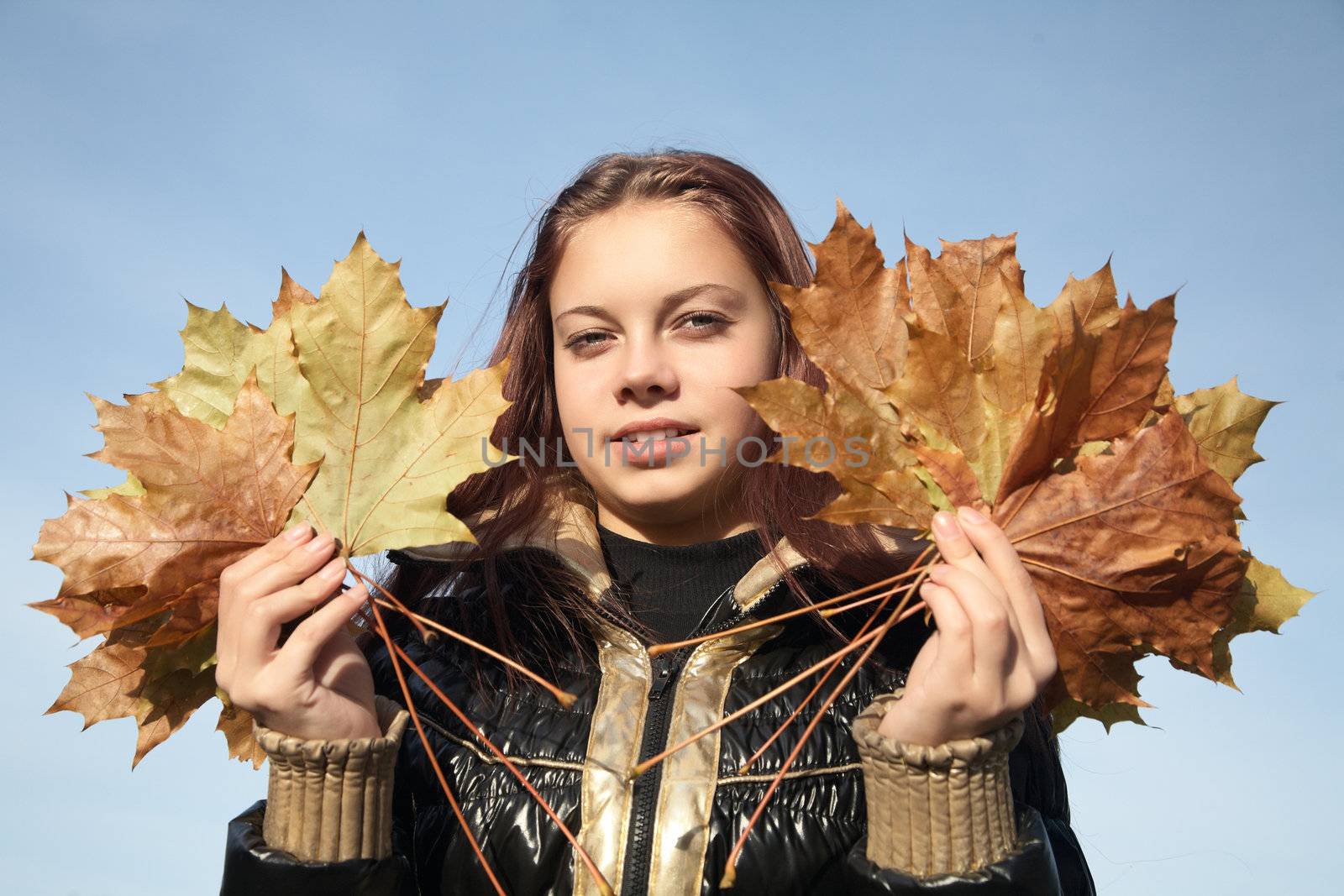 Portrait of  girl with yellow leaves against the blue sky