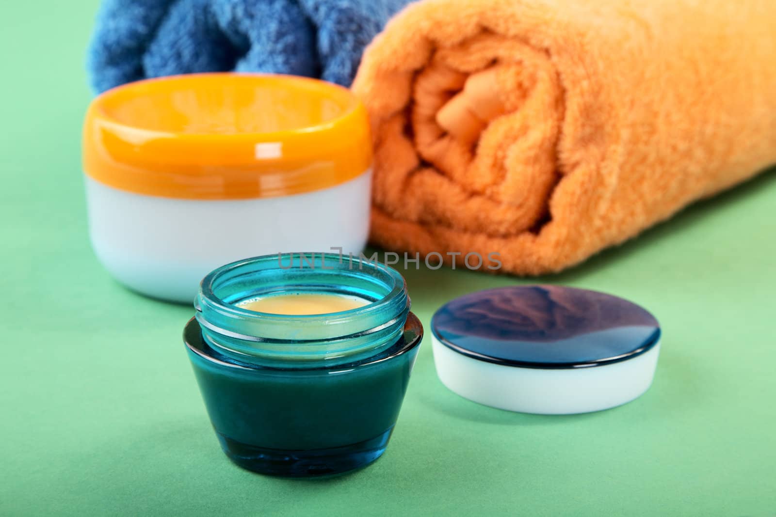 Cosmetic cream and towels on a green background