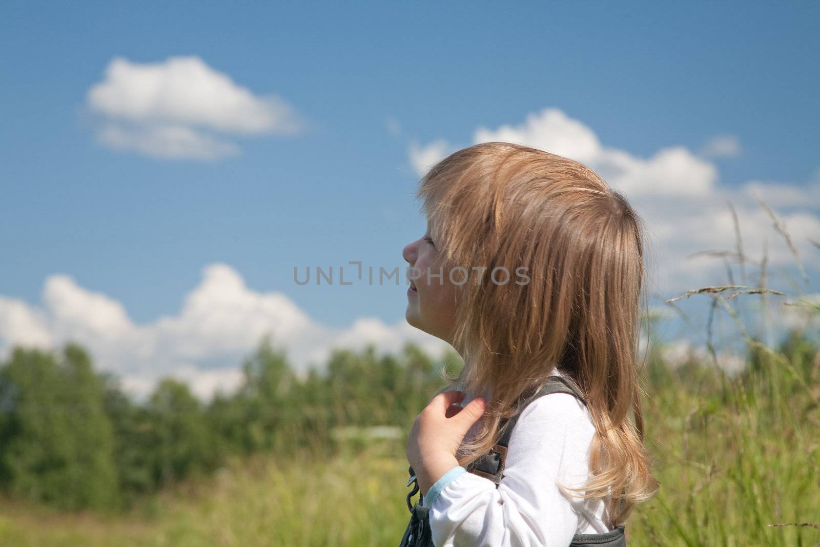 little girl looks at the sky with clouds