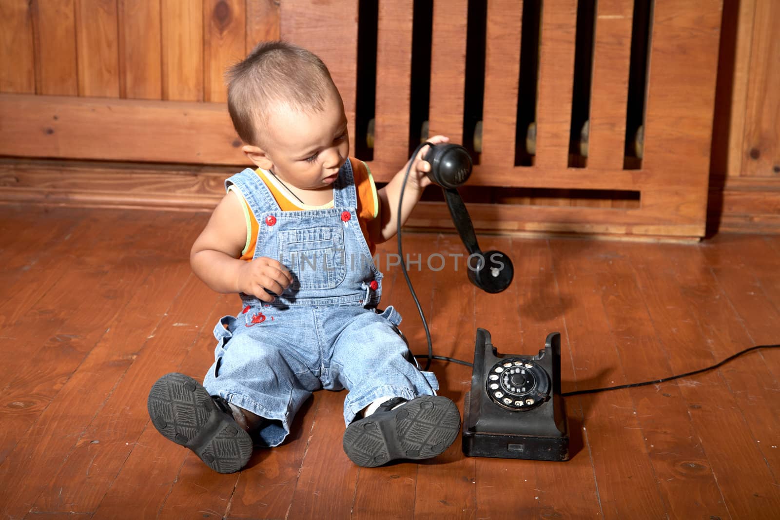 The little boy plays old phone sitting on a floor