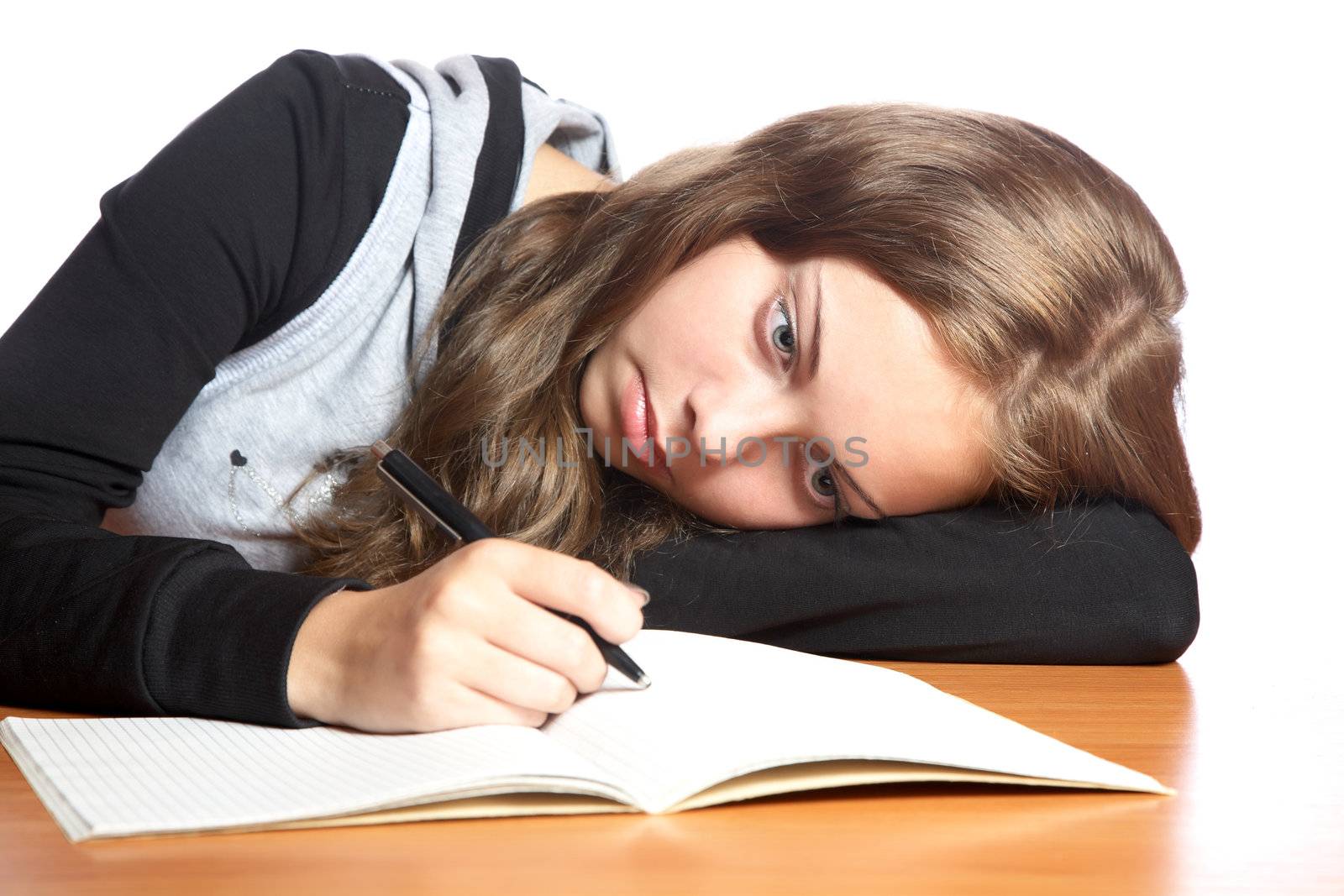 The girl-teenager looks in  writing-book on a white background