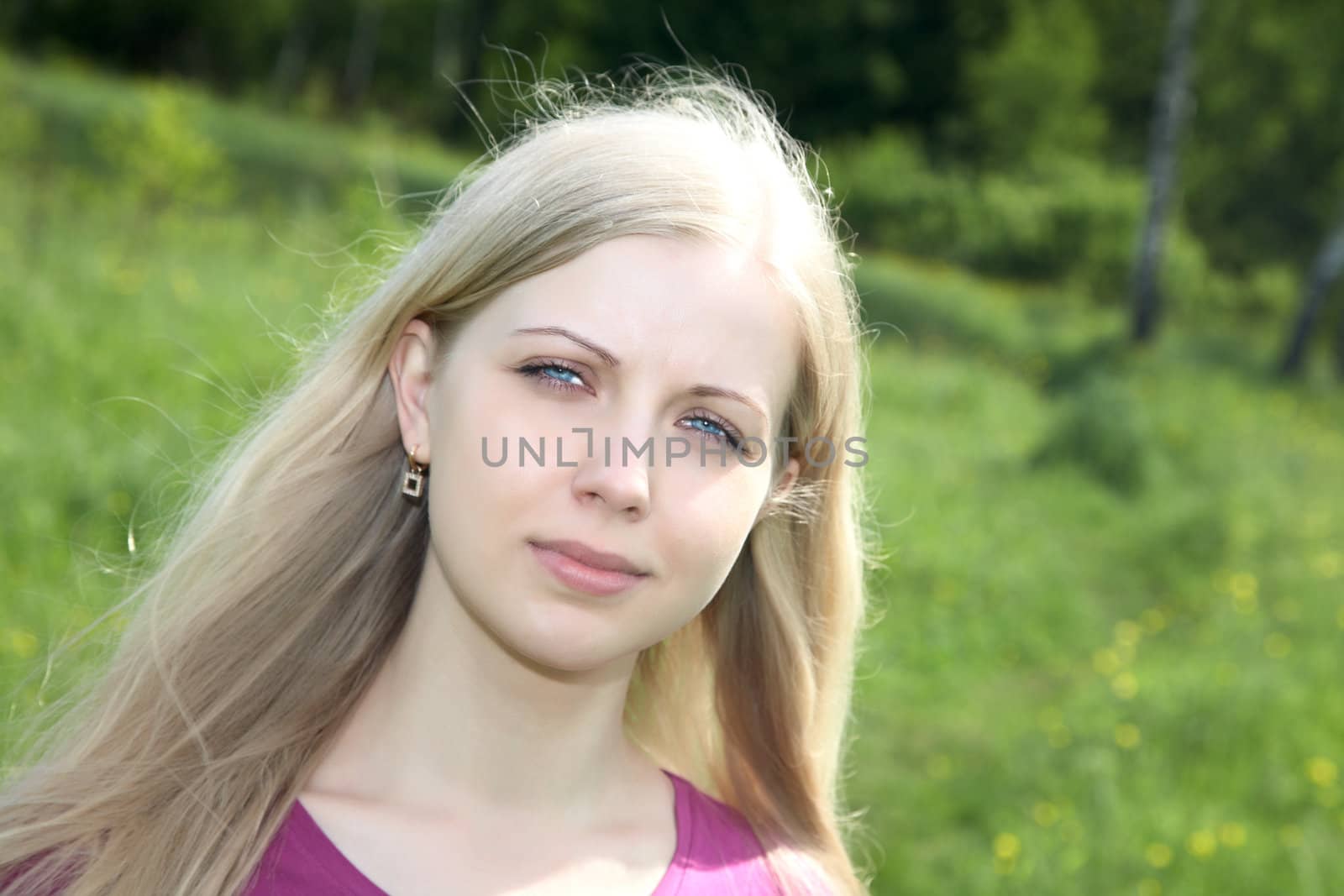 Portrait of the girl in spring day against a green grass