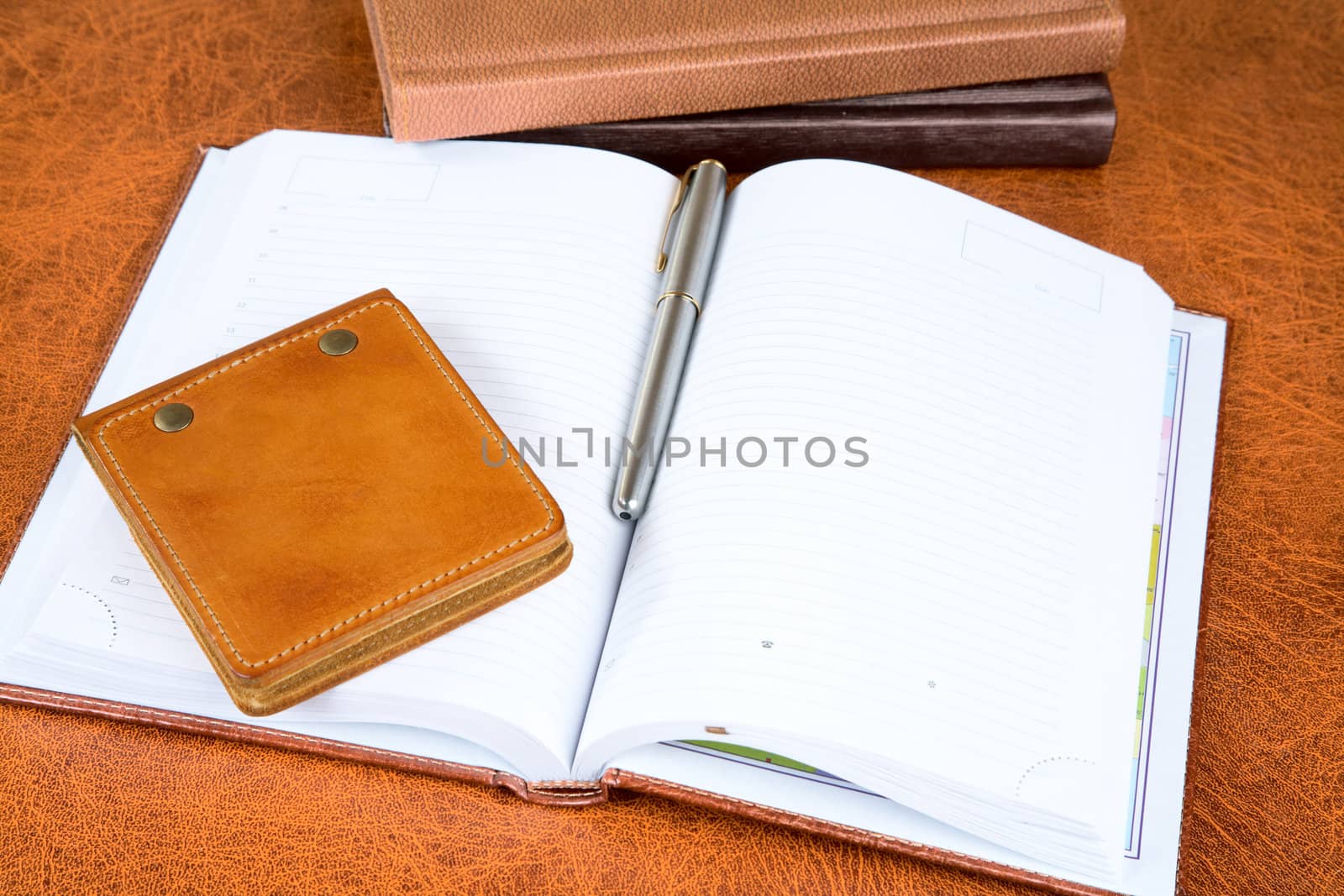 Leather organizers and fountain pen on a textural background