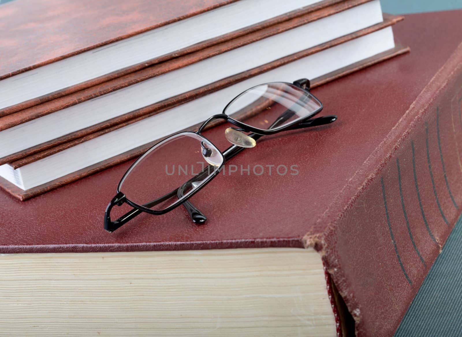 Pile of books and glasses on old thick volume