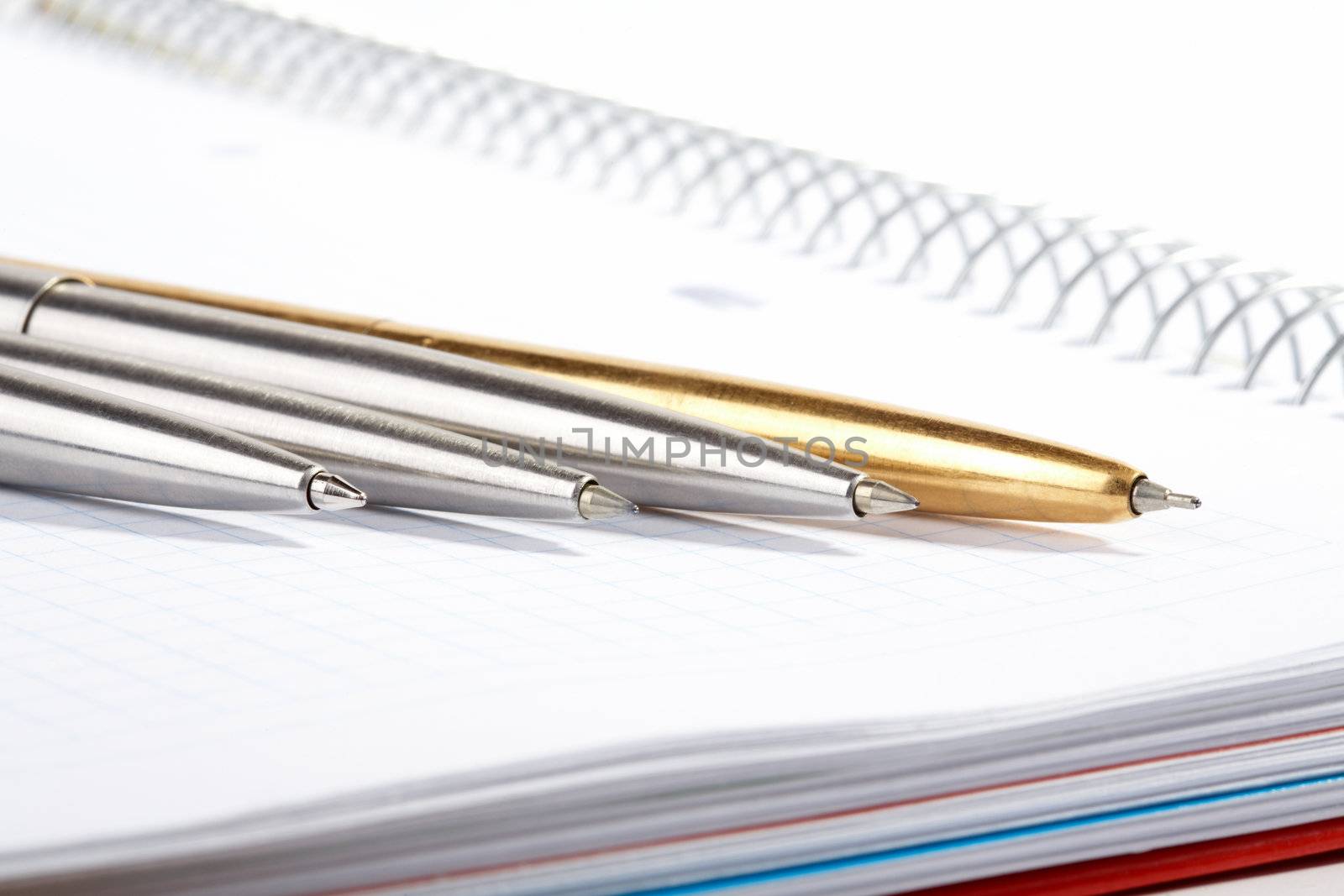 line of ball-point pens lays on a writing-book