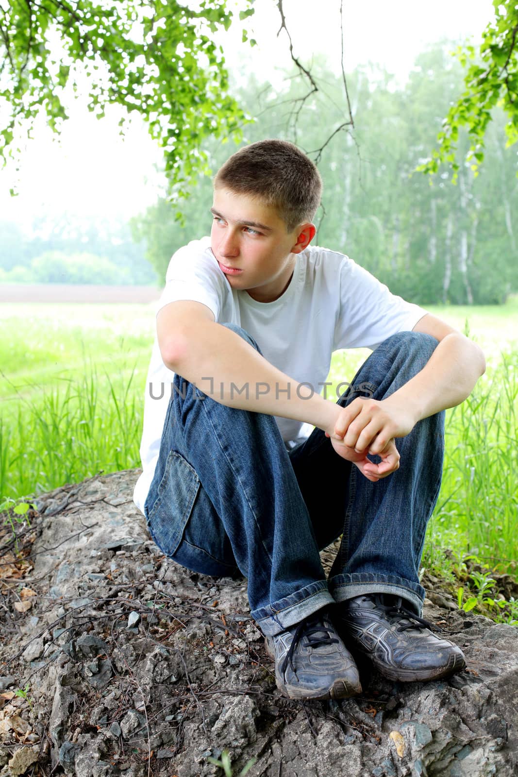 sad teenager sitting in the forest alone