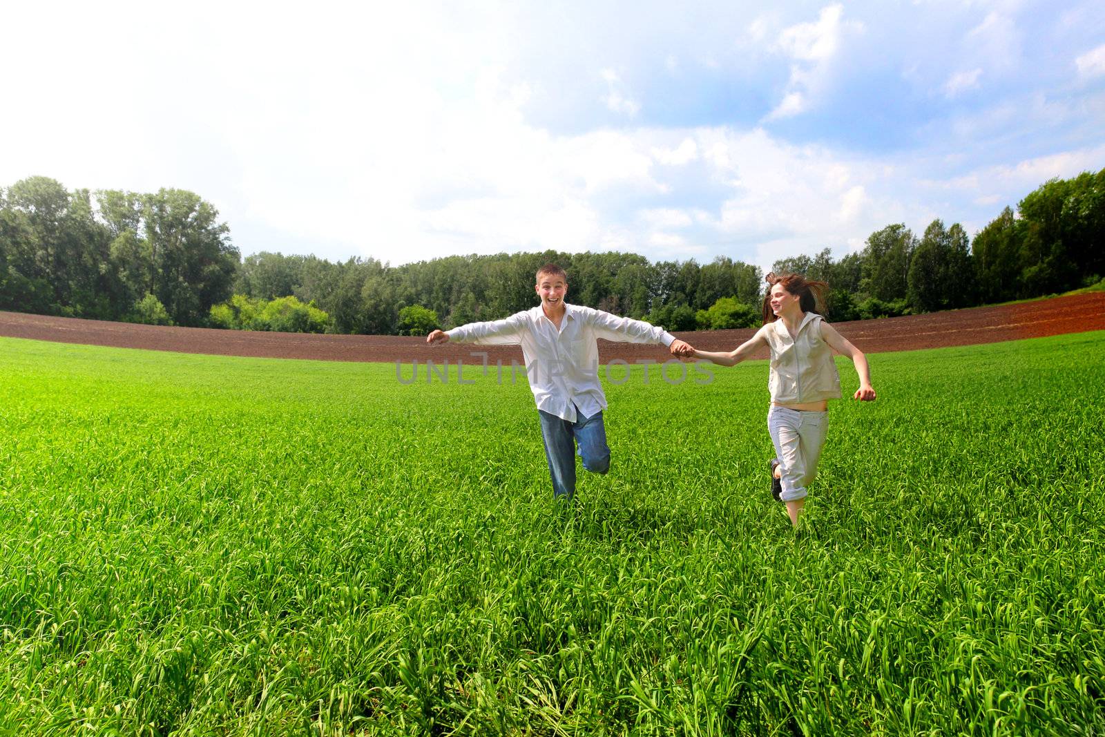 happy couples running in the summer field