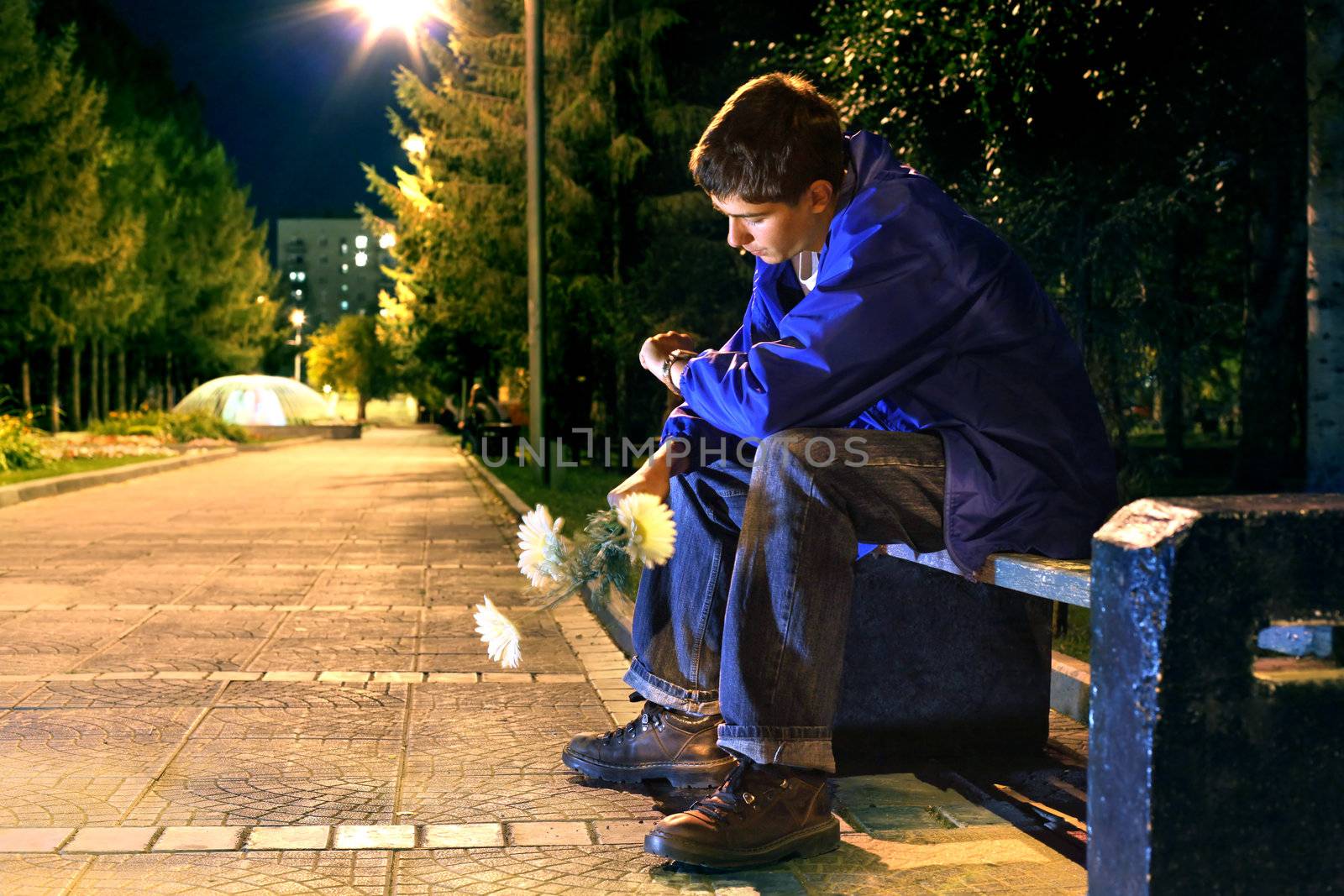 teenager in the evening park in expectation of girlfriend looking on the watch