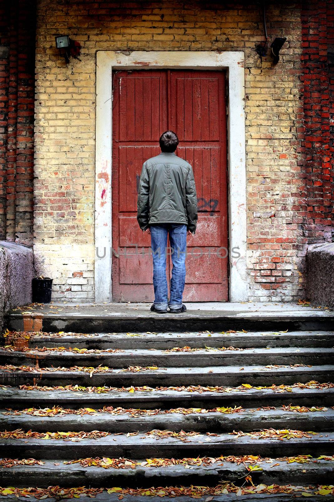 man stand on stairs of an old house with closed door