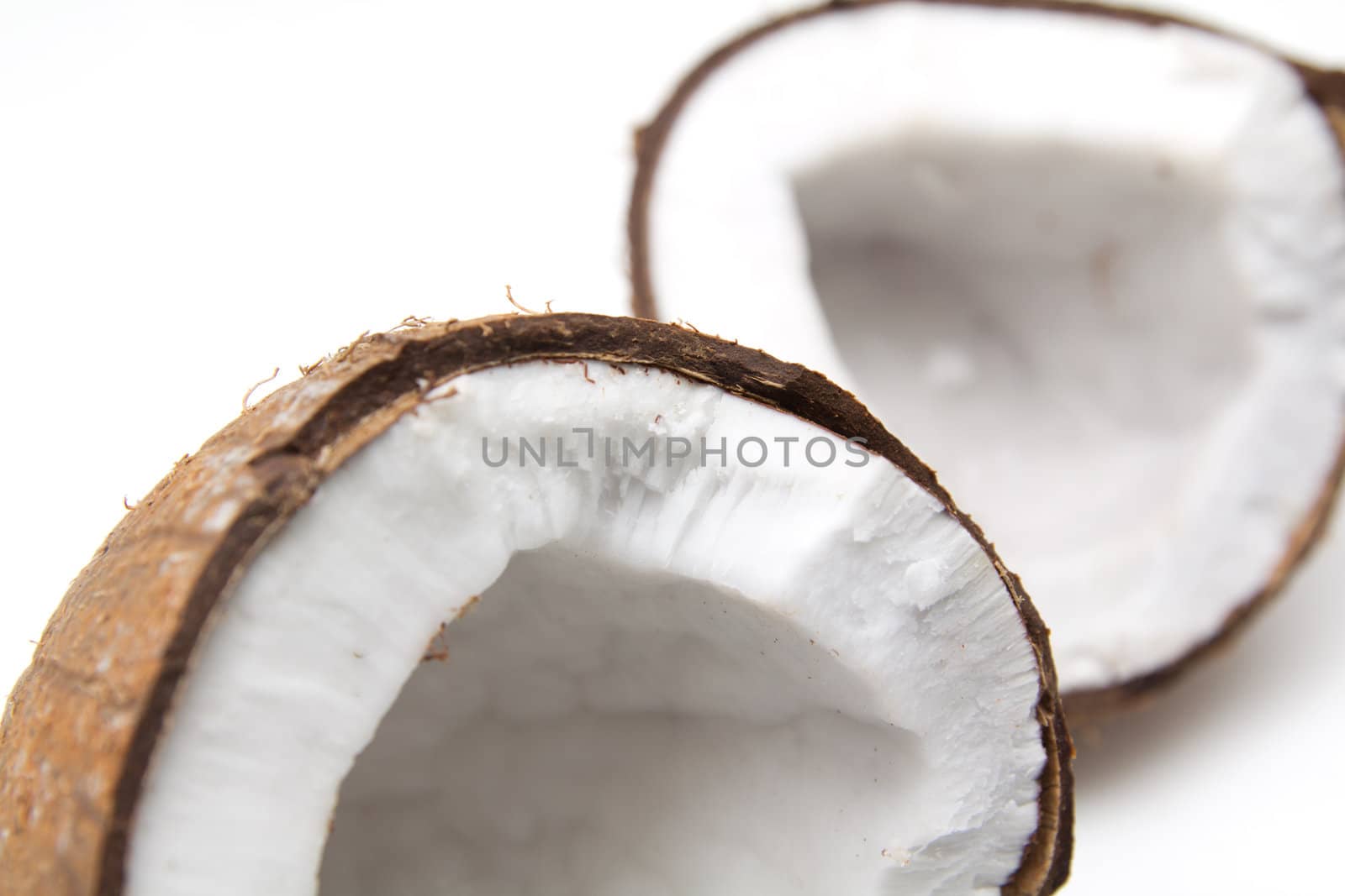 Closeup of cracked coconut on white background with light shadow. Shallow focus depth on front coconut 