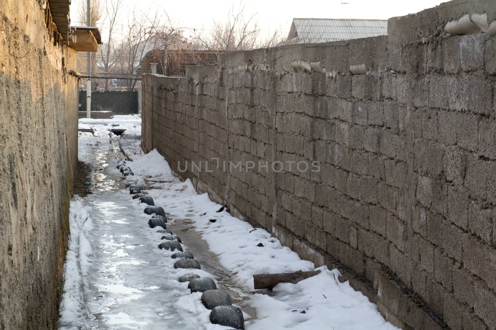 passage between the old houses with tires in the snow