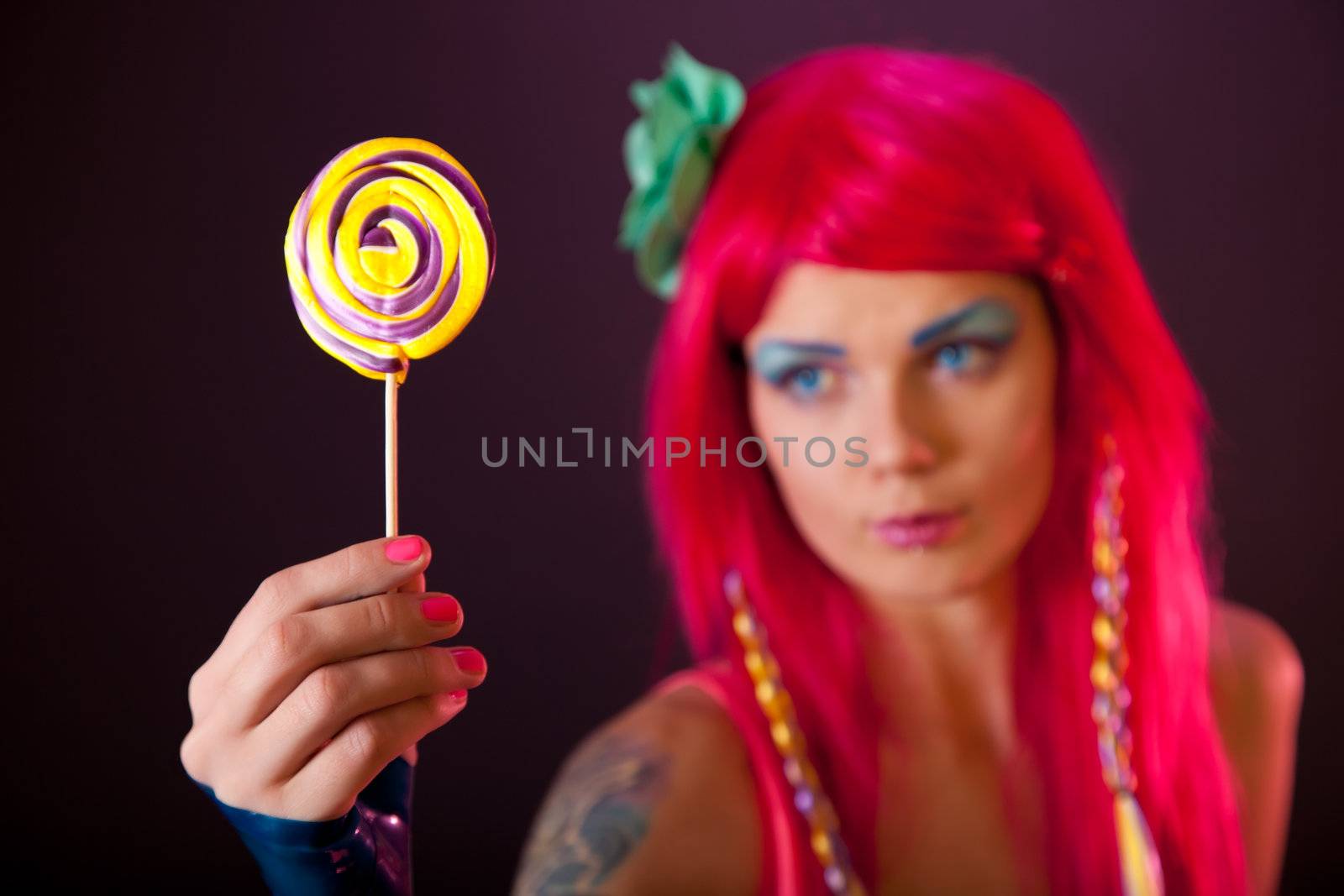 Girl with pink hair holding lollipop, focus on candy 