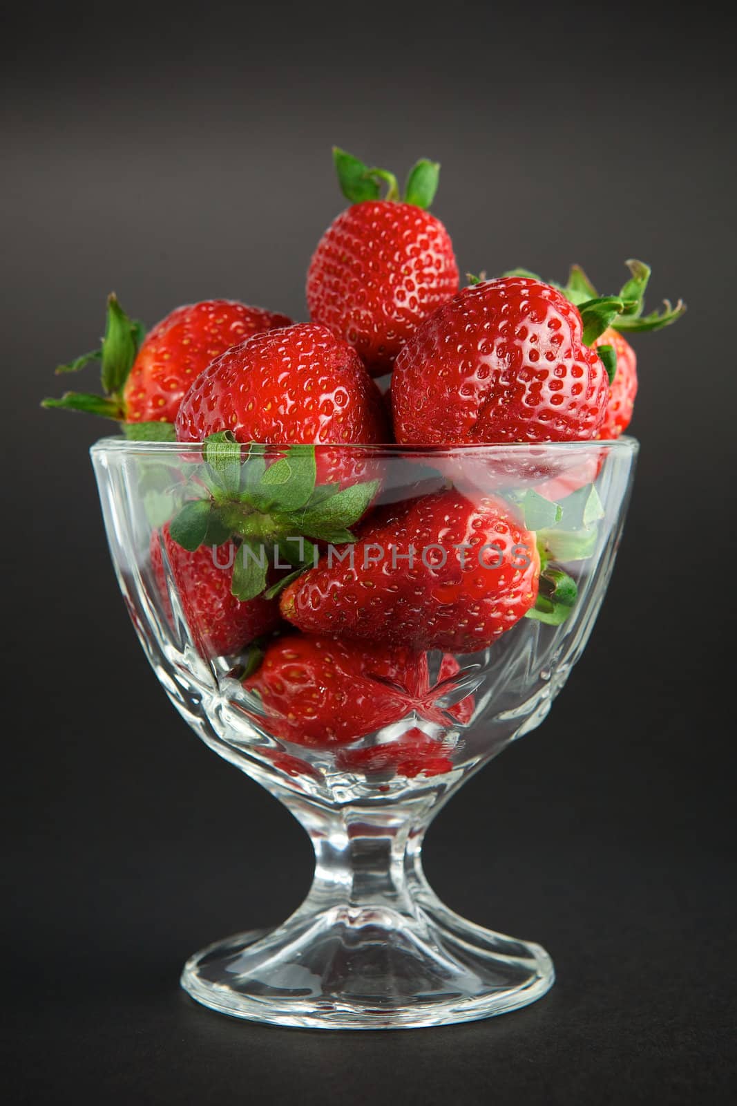 Strawberry in glass container on black background