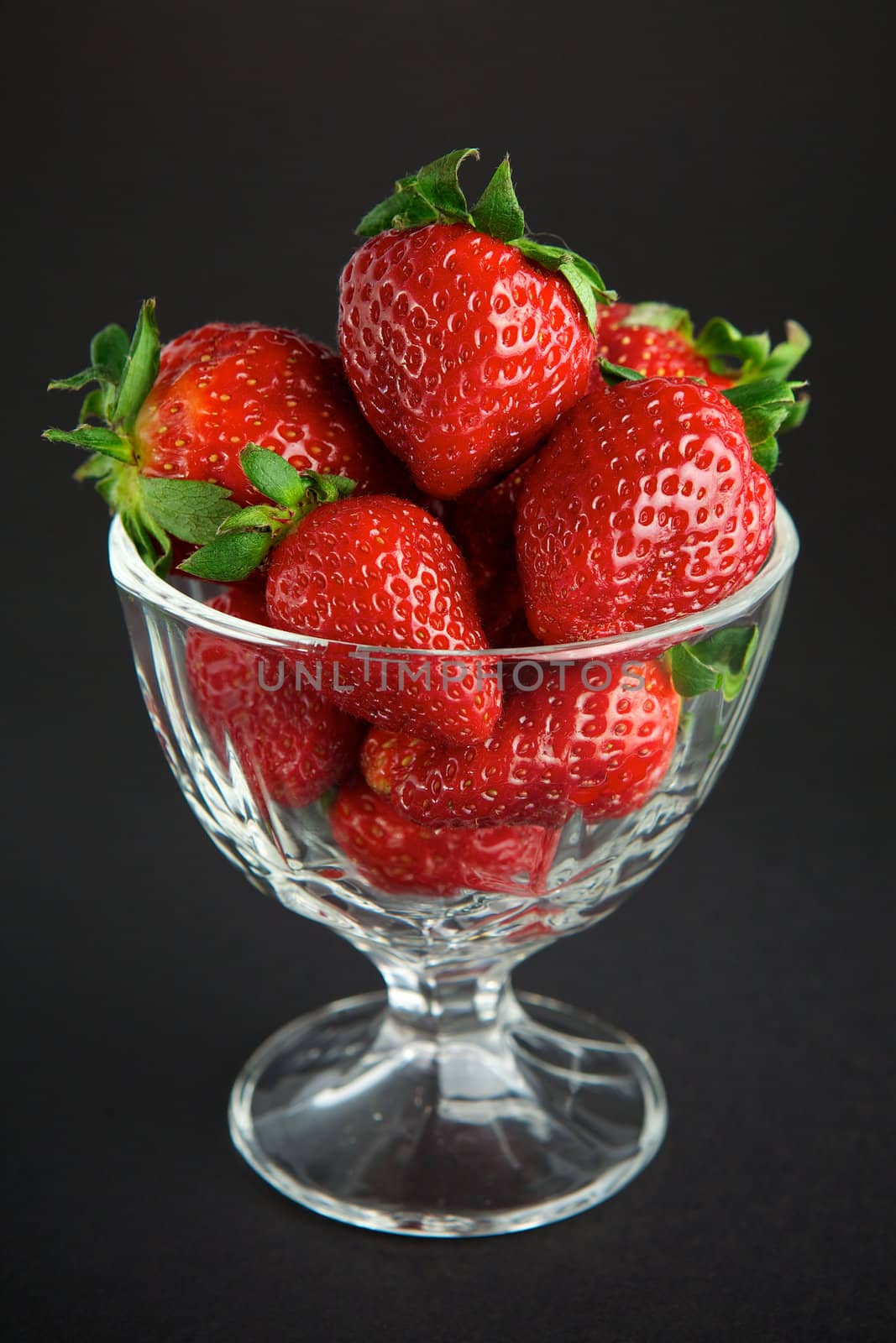 Strawberry in glass container on black background