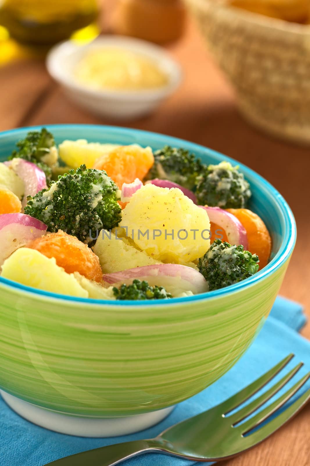 Green bowl full of fresh salad of potato, broccoli, mandarin and onion with mayonnaise (Selective Focus, Focus on the broccoli and the potato in the middle of the bowl)