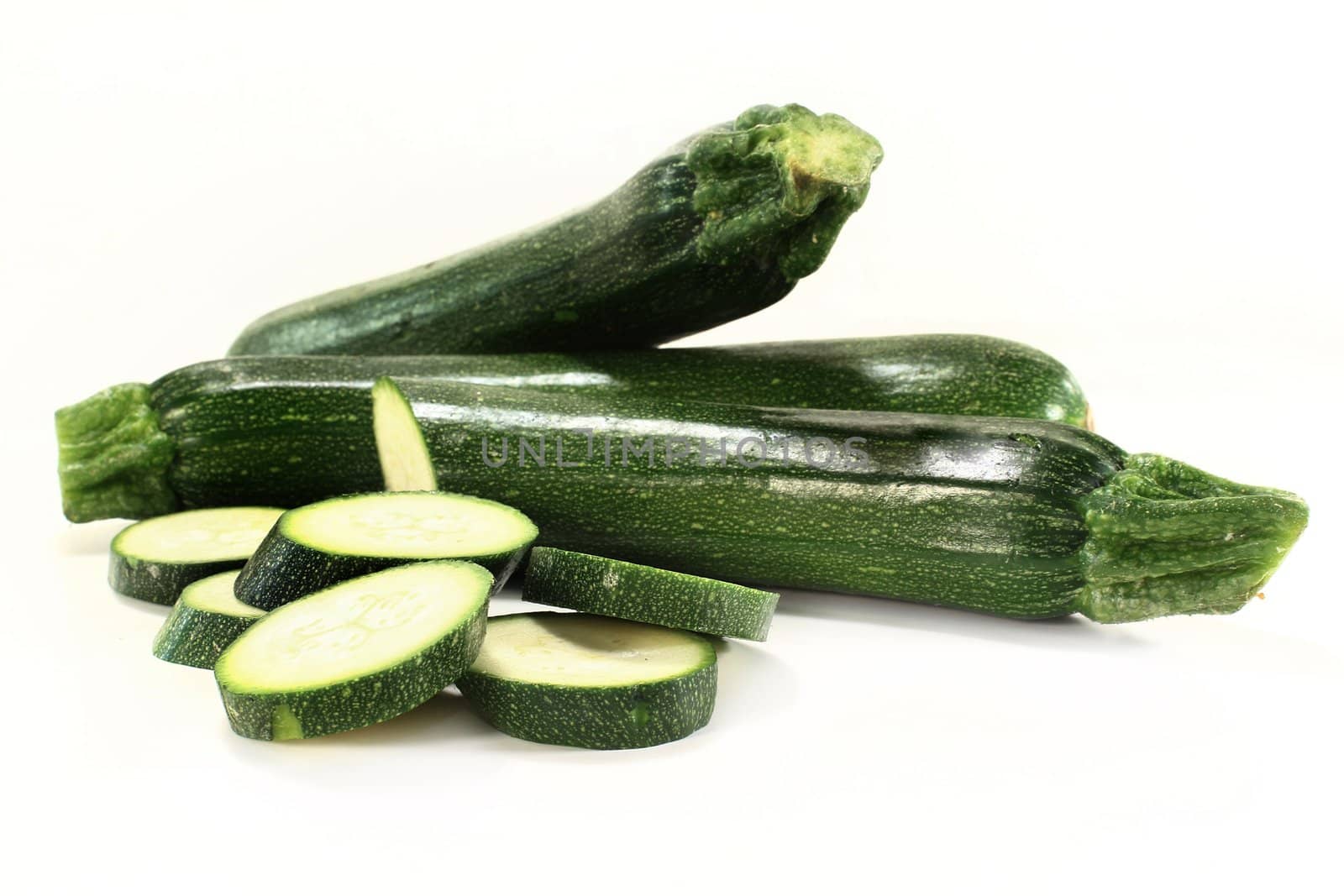 three green zucchini on a white background