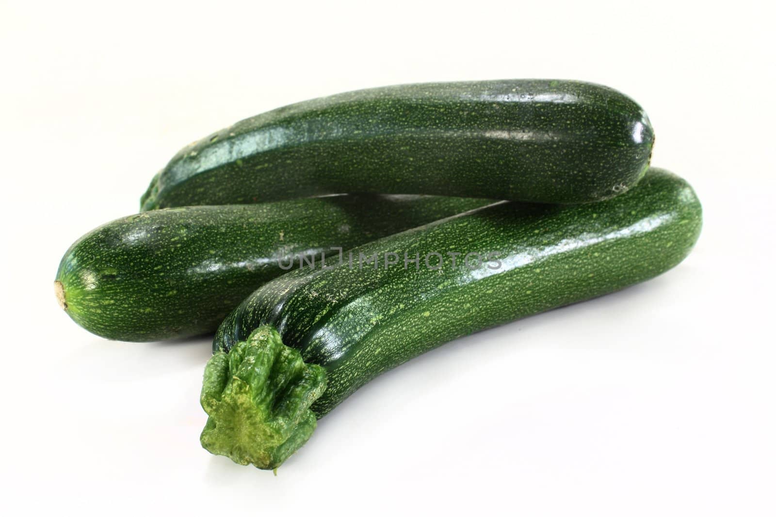 three green zucchini on a white background