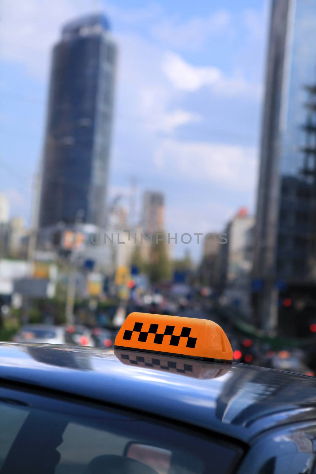 A cab in an urban area with the lit taxi sign on top of its roof