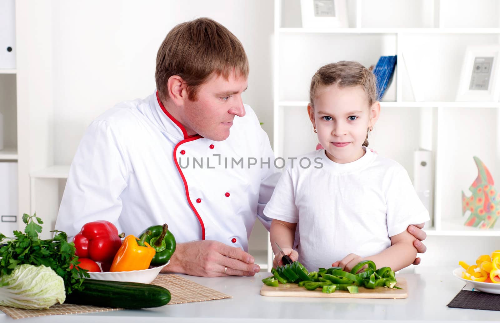 portrait of father and daughter cooking salad together in the kitchen