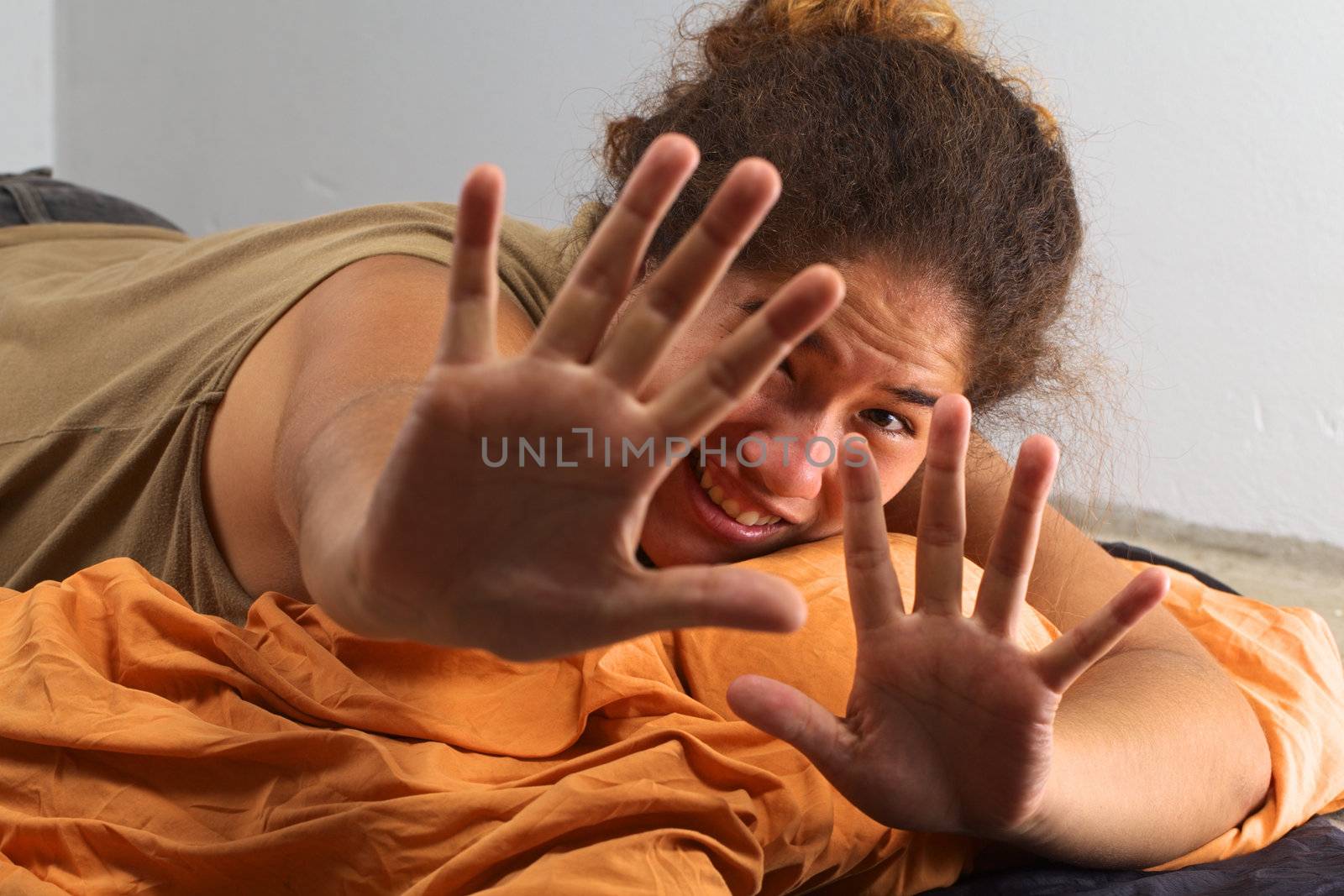 Young Peruvian woman lying on a sleeping bag on the floor doesn't want to be photographed (Selective Focus, Focus on the face of the woman)