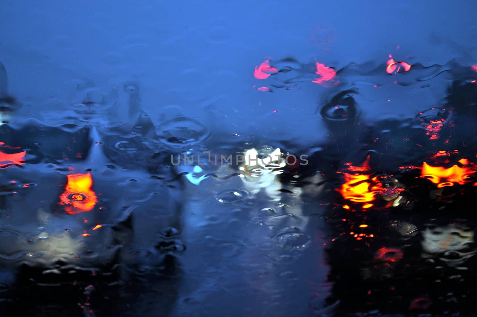 Rainy twilight traffic at a red light.