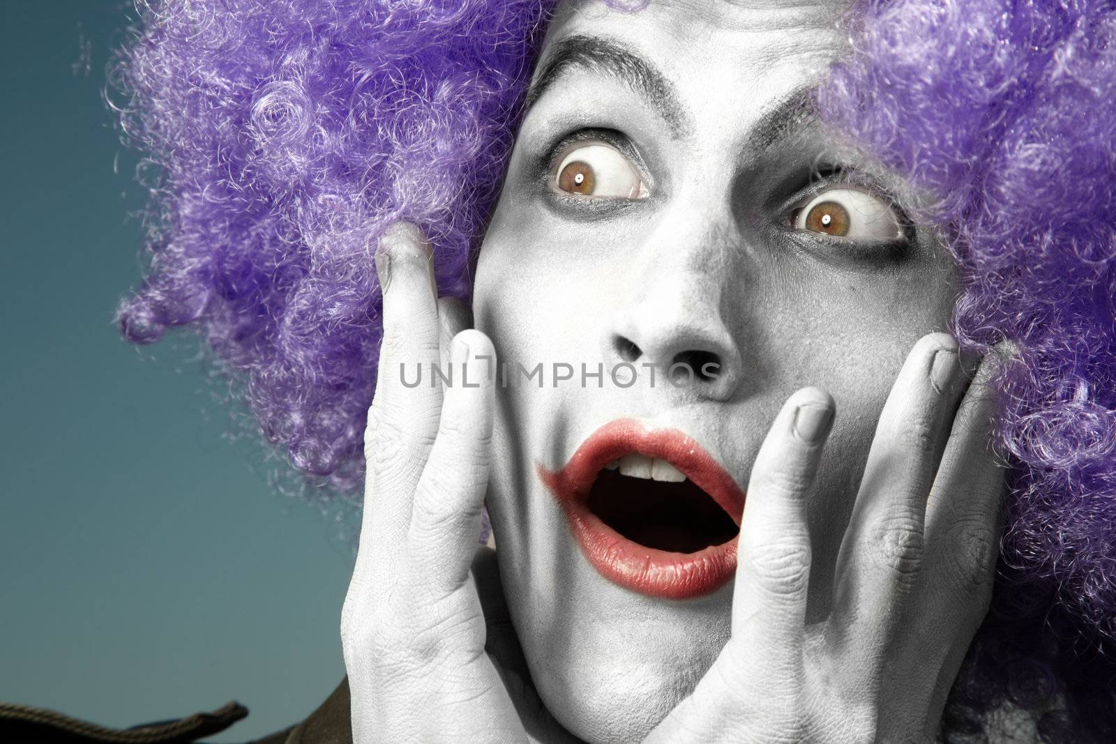 Surprising clown with purple wig on a blue background