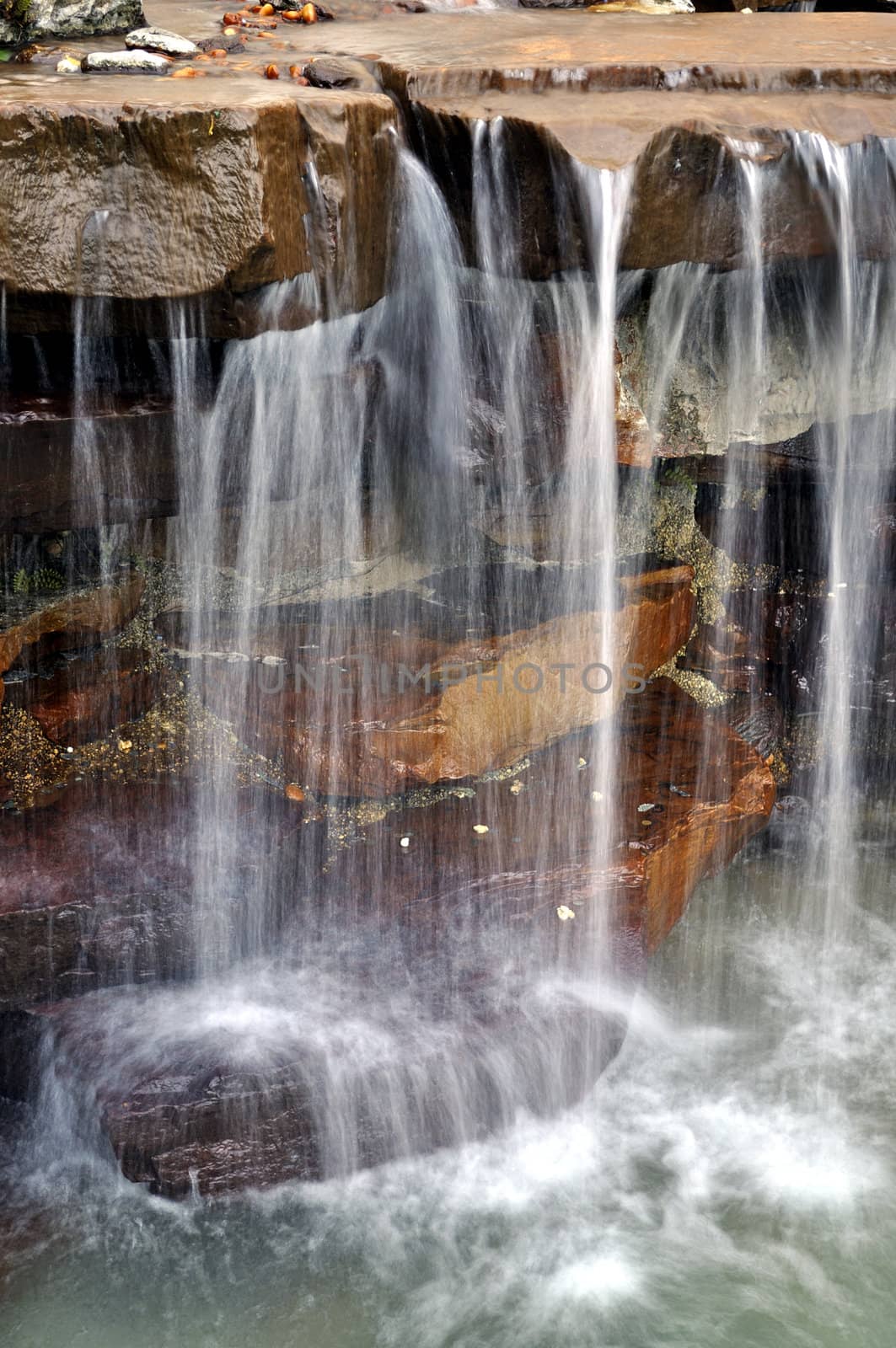 Water flowing over rocks in a small man-made waterfall.