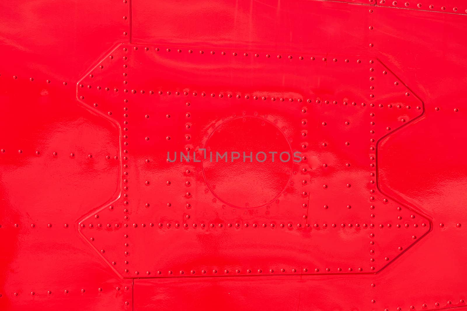 Bright red painted riveted metal sheet skin of airplane fuselage background texture pattern