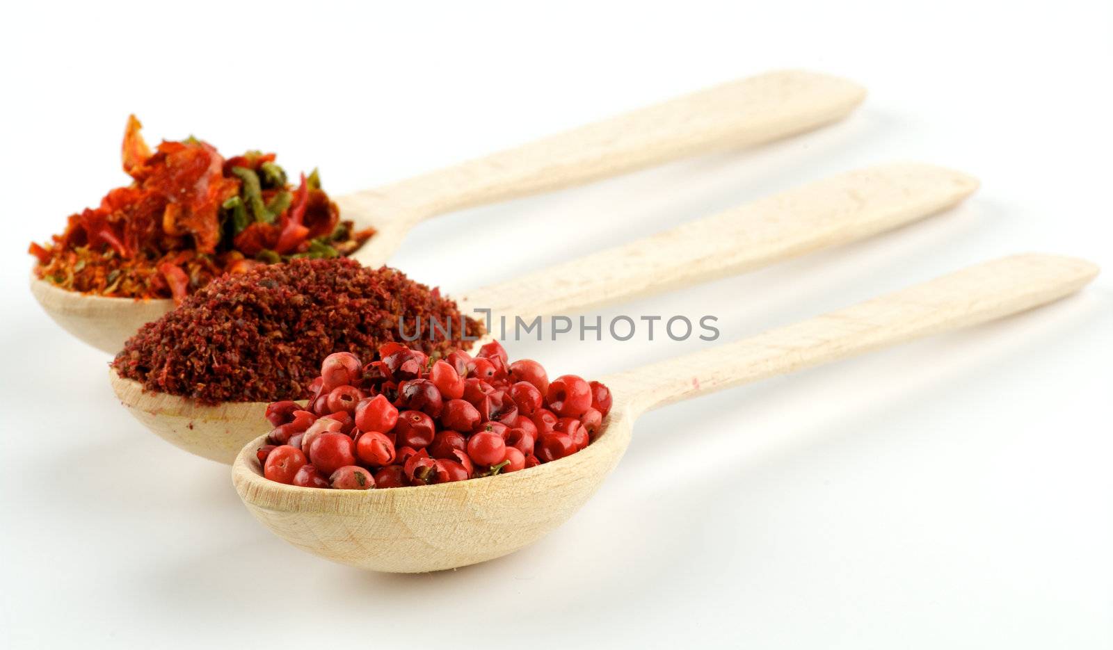 Red pepper, Cayenne Pepper and Paprika in wooden spoons isolated on white background