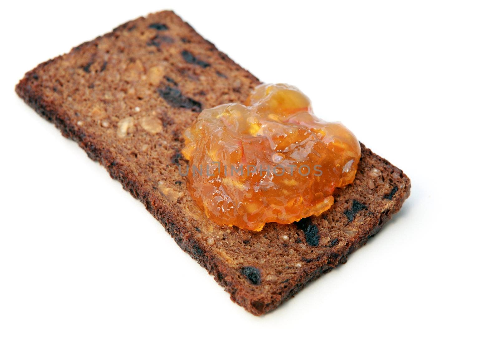 piece of grain bread with orange jam over white background