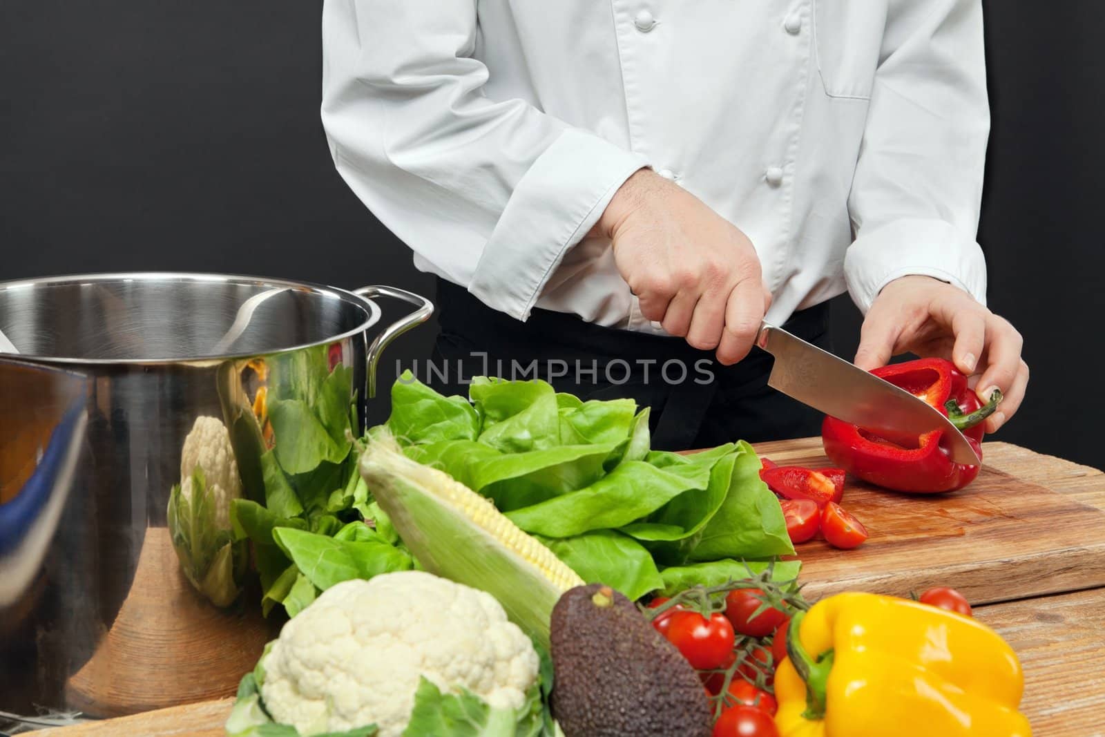Photo of a chef chopping vegetables on a wooden cutting board.