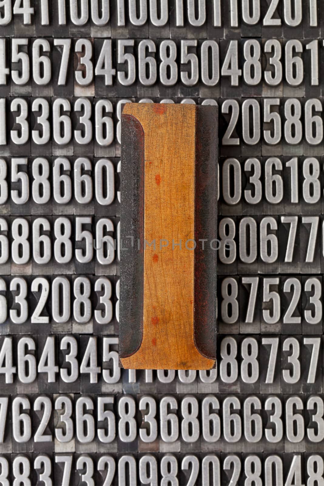 number one in vintage letterpress wood type against background of random metal numbers