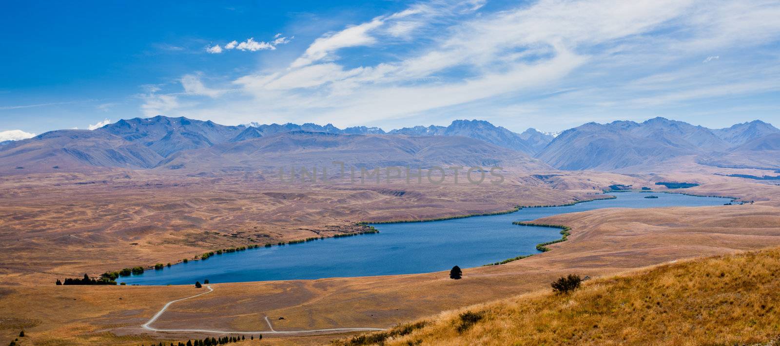 Lake Alexandrina in dry grassland in Central Canterbury with ranges of suthern alps, South Island, New Zealand