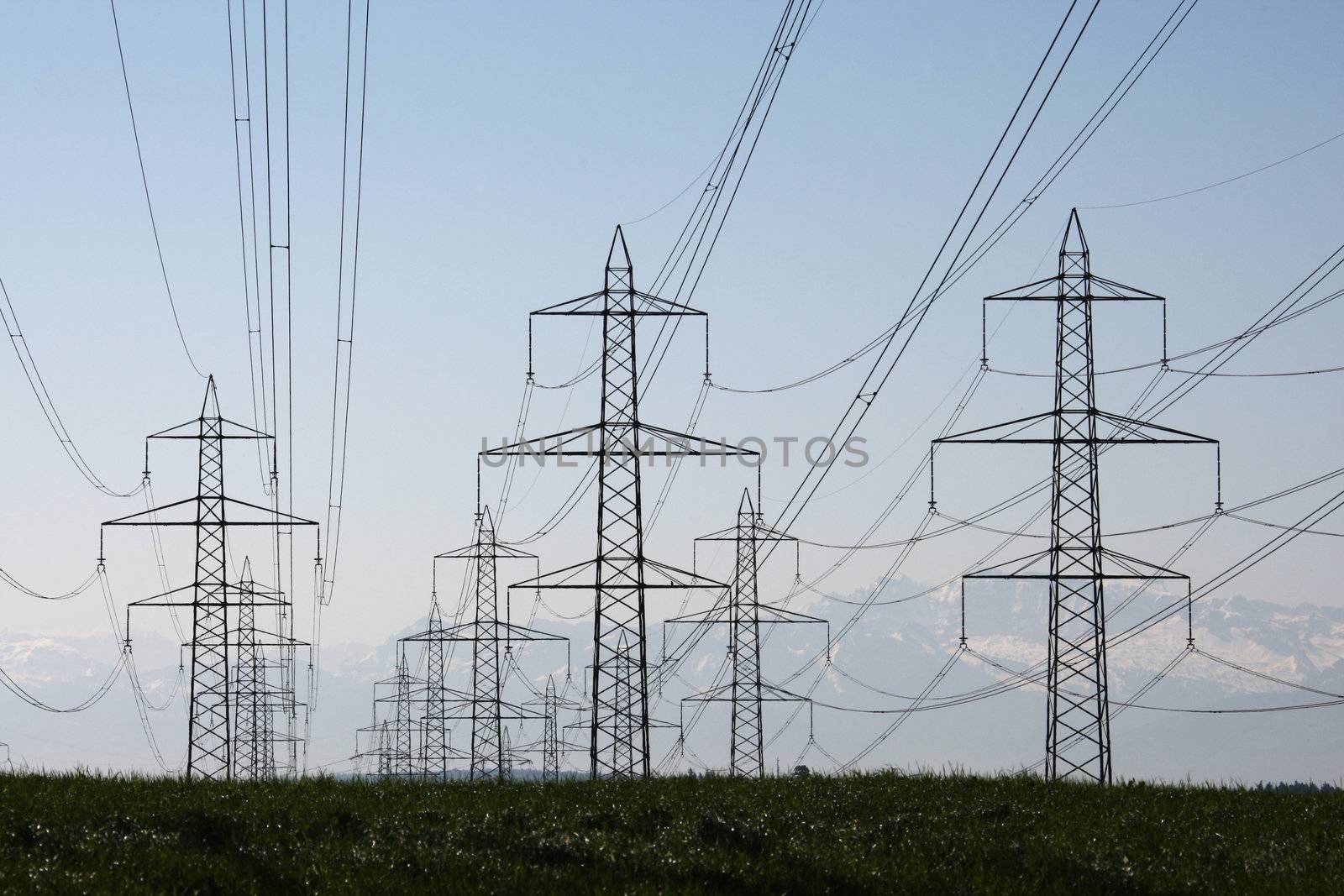 power lines over a meadow with mountains in the background