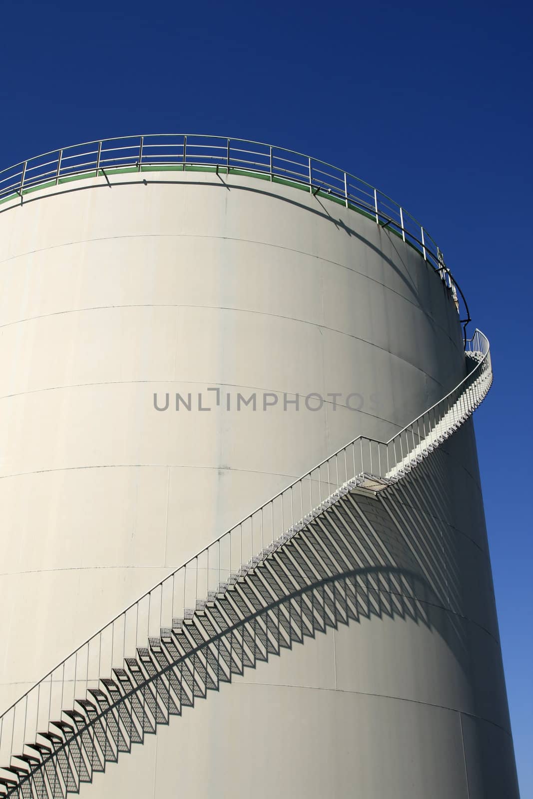 spiral staircase around oil storage and blue sky