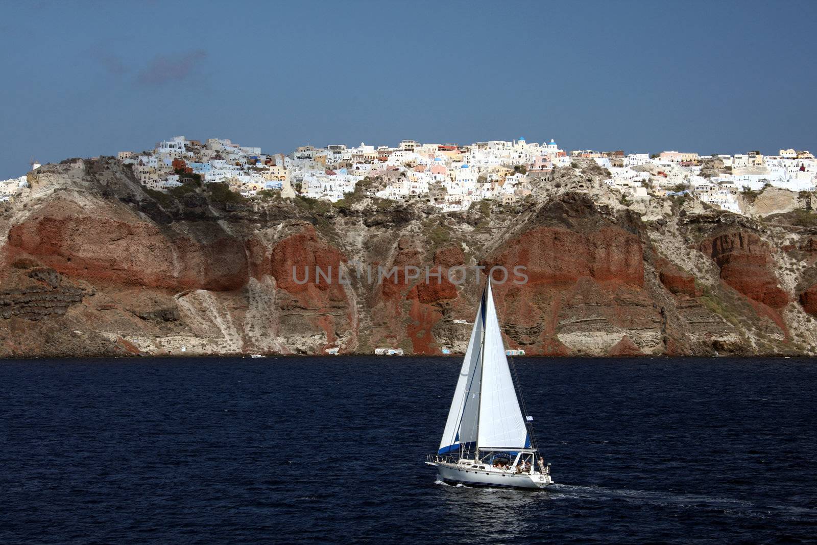 Sailboat on Mediterranian sea with Santorini village of Oia in background