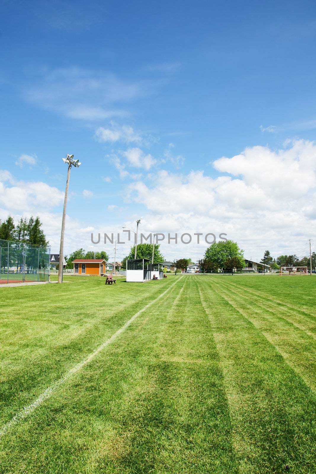 View from the corner of a soccer or football field with dug outs and lighting in a small town public recreation park.