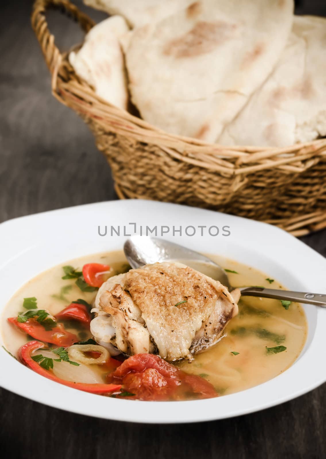 Chicken sour soup with homemade bread on rustic background