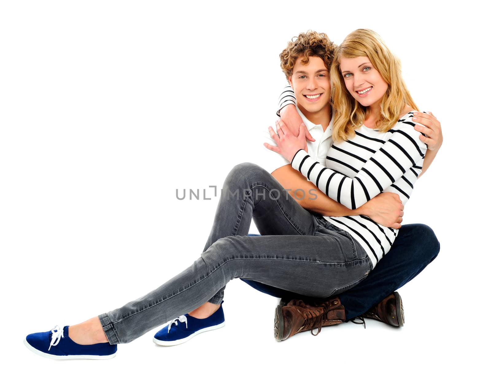Girlfriend sitting on her partners lap against a white background. Couple embracing