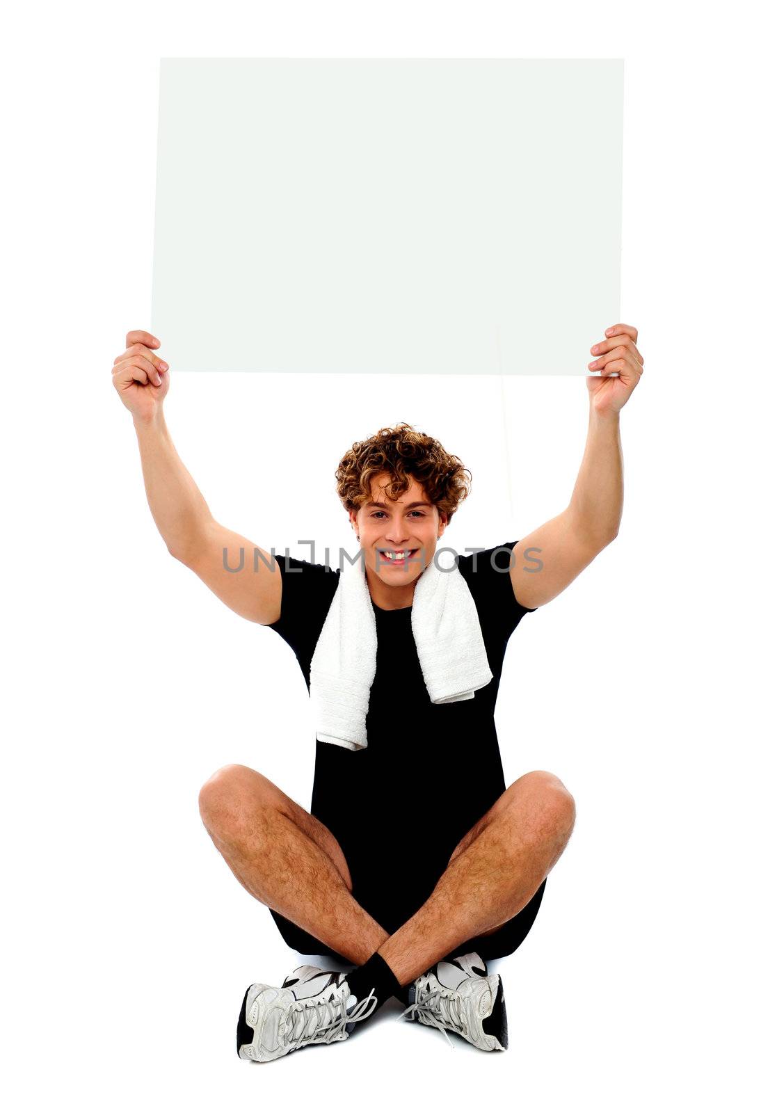 Handsome athlete holding blank placard over his head. Towel wrapped around neck
