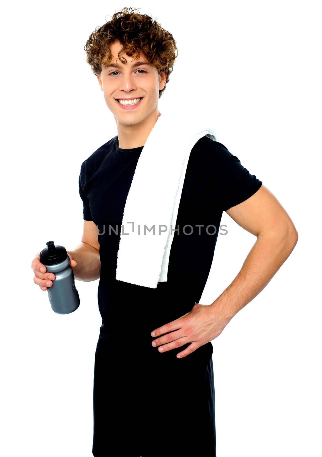 Smiling young man holding towel on shoulders and sport bottle isolated over an isolated background